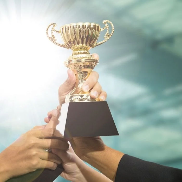 Um troféu sendo levantado por várias mãos